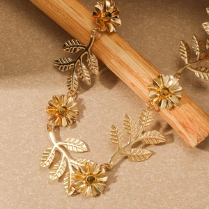 Makroaufnahme eines goldenen Metall-Stirnbands mit Blumen und Blättern auf Beige