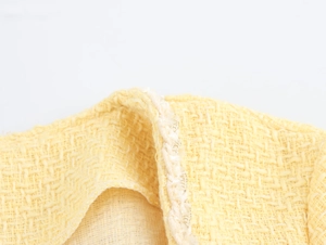 Close-up of yellow tweed fabric texture and high-quality edge stitching on dress