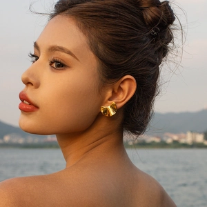 Close-up of a model wearing a minimalist 18k gold-plated irregular textured stud earring