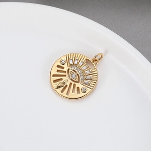 Ciondolo a forma di occhio in oro 14k con zirconi su un piatto di ceramica bianca