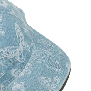 Close-up of white butterfly embroidery on premium light blue denim baseball cap detail