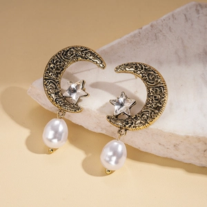 Vintage gold moon earrings with star crystal and baroque pearl on a beige stone base