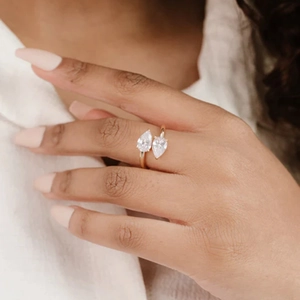 Detail of a gold double teardrop zircon ring worn by a model for elegant styling