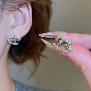 Gros plan de boucles d'oreilles cheval à bascule argentées serties de zircons brillants
