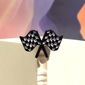Macro detail of crossed checkered racing flag enamel pin on a white geometric stand