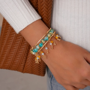 Detail of layered bohemian cuff with teal beads, gold wires, and metallic pendants