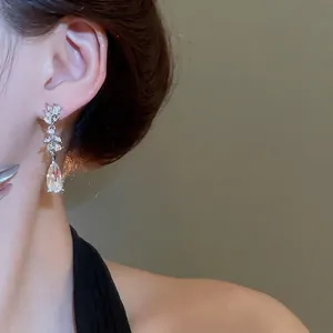 Elegant silver drop earrings with marquise crystals on model against warm background