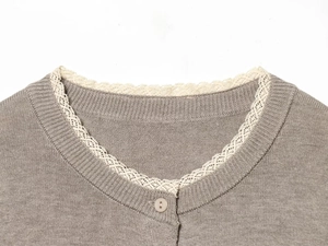 Close-up of light gray knit cardigan featuring round neck with white lace trim and button