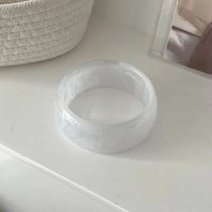Detail of white marble textured resin bangle on a minimalist white surface with soft light