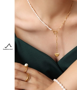 Detail of gold stainless steel heart pendant necklace with pearls and toggle clasp
