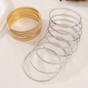 Detail showing the gold and silver metallic texture of these minimalist bangles on white fabric