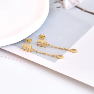 Golden tassel earrings with square and marquise zircon crystals on elegant white display