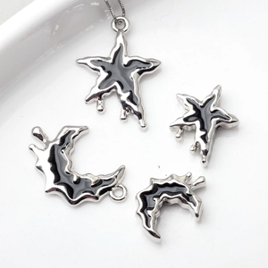 Silver alloy star and moon charms with black oil drop finish on white ceramic background