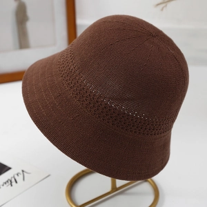 Details eines dunkelbraunen Strickhutes mit Lochmuster auf einem Metallständer