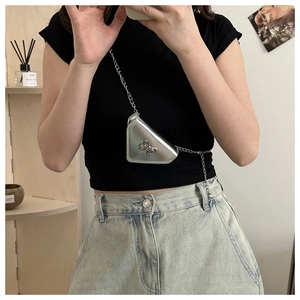 Détail du sac bandoulière triangulaire argenté avec ornement papillon et chaîne en métal