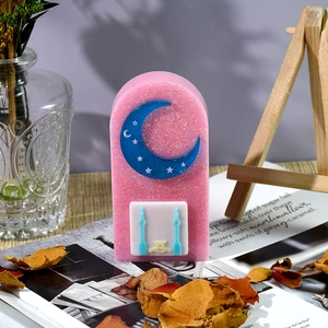 Dettaglio ornamento in resina glitter rosa con luna blu e rilievo di edificio bianco