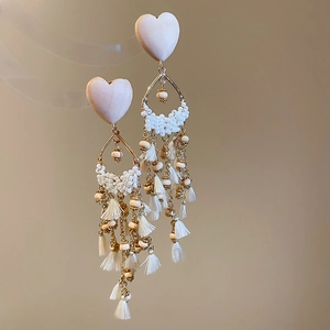 Detail showing pink heart and white beaded droplet earrings with elegant fringe tassels