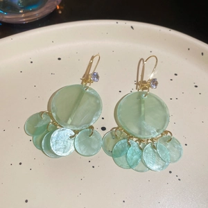 Detail of mint green shell fringe earrings with gold hook and cubic zirconia stone