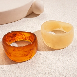 Artistic resin bangles with marble texture in amber and cream on a sandy surface