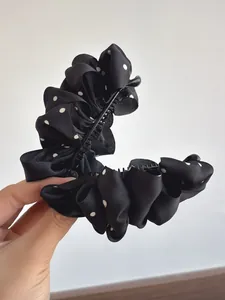 Detail of elegant black polka dot pleated satin banana hair clip with ruffled texture