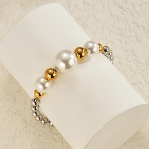 Detail view of stylish stainless steel bead bracelet with pearls on white display stand