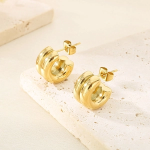 Détail macro des boucles d'oreilles créoles creuses en acier doré 18 carats en C