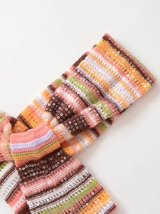 Makro-Detail des bunt gestreiften Strickstoffs mit schimmernden Pailletten in Nahaufnahme