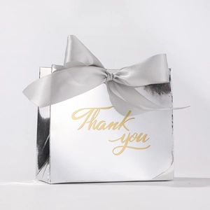 Detail of silver wedding favor box with a satin bow and gold Thank You lettering