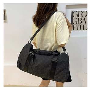 Large black travel duffel bag with textured embossed fabric shown being carried by a model