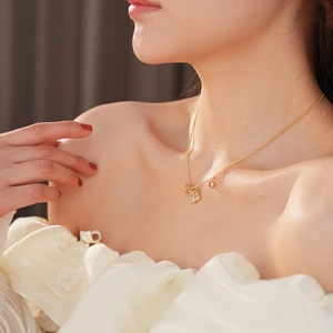 Primo piano della collana con ciondolo a trifoglio in oro 18 carati indossata dal modello