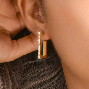 Detail of 18K gold-plated rectangular earrings with crystals worn on a model's ear
