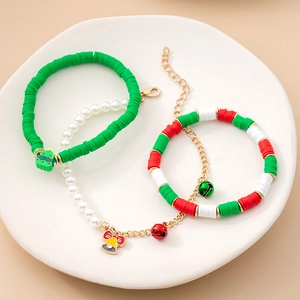 Detailed close-up of Christmas charm bracelets with reindeer and bells on white ceramic plate