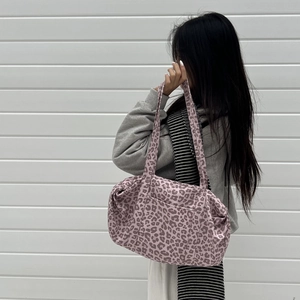 Dettaglio della borsa tote leopardata rosa in pelle scamosciata indossata da modella
