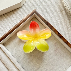 Rainbow gradient plumeria hair claw clip with vibrant spring colors on linen backdrop