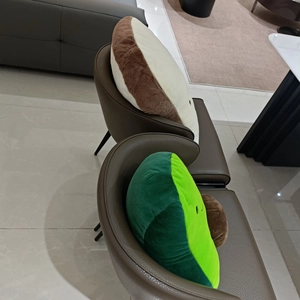 Plush avocado and toast bread pillows displayed on a stylish leather dining chair