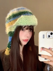 Detailed close-up of the plush texture and colorful striped knit pattern on the earflap hat