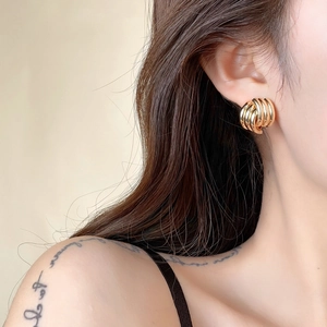 Close-up of minimalist gold geometric multilayer hoop earrings worn by a female model