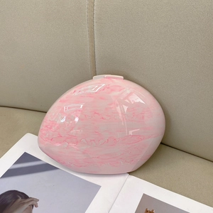 Detail of pink marble pattern oval clutch bag with glossy resin finish and metal clasp