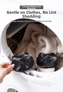 Macro shot of black cat-shaped laundry sponge catching hair and lint in washing machine