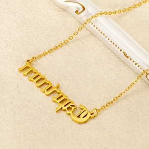 Détail d'un collier plaqué or avec un pendentif stylisé portant l'inscription Mummy
