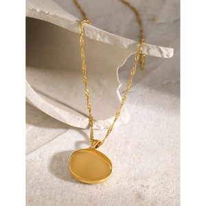 18k gold plated stainless steel necklace with oval disc pendant on stone background