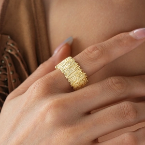 Detailed close-up of a wide gold textured ring with unique metallic wrinkled pattern