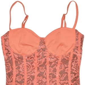 Détail de la robe caraco en dentelle corail montrant les motifs et bretelles fines