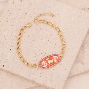 Detail of gold bracelet featuring red enamel charm with white clouds and pink zircon border