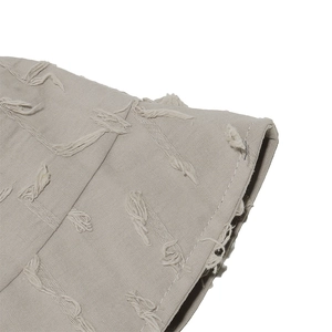 Macro view of light grey cotton bucket hat featuring decorative tassel fringe and stitching