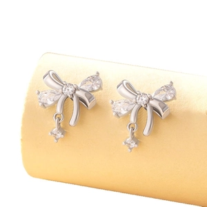 Silver bow knot earrings with cubic zirconia charms on display stand, high-quality titanium steel