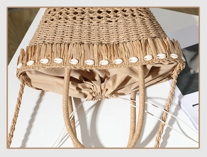 Dettaglio della borsa in paglia intrecciata con nappe di conchiglie e fodera interna