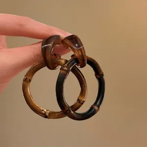 Dettaglio di orecchini a cerchio in stile bambù con texture marrone e design vintage