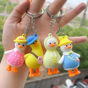 Cartoon duck keychain set featuring colorful outfits and metal rings shown in hand