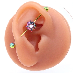 Gros plan sur un piercing industriel arc-en-ciel avec pendentif tournesol et perle blanche